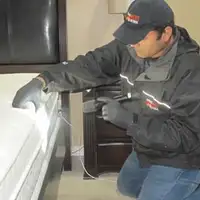 Bed bug inspection technician checking a mattress and bed frame for signs of infestation in Salt Lake City, UT