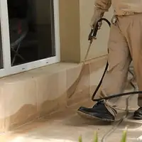 General pest control technician spraying exterior perimeter around a home in Salt Lake City, UT
