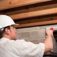 Termite inspection technician checking a basement wall and framing for termite activity in Salt Lake City, UT