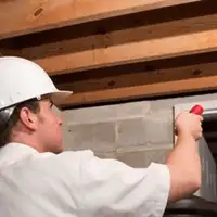 Termite inspection technician checking a basement wall and framing for termite activity in Salt Lake City, UT